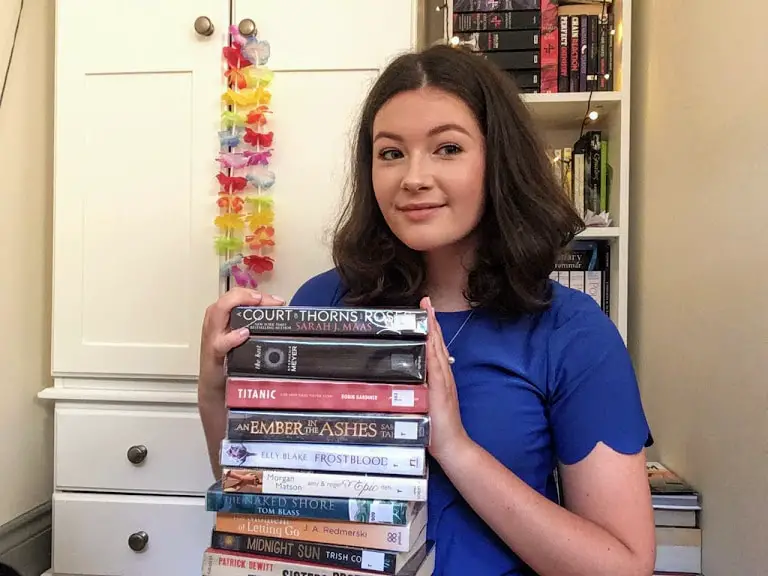 Girl holding stack of books. My 2020 goal is to read 50 books.