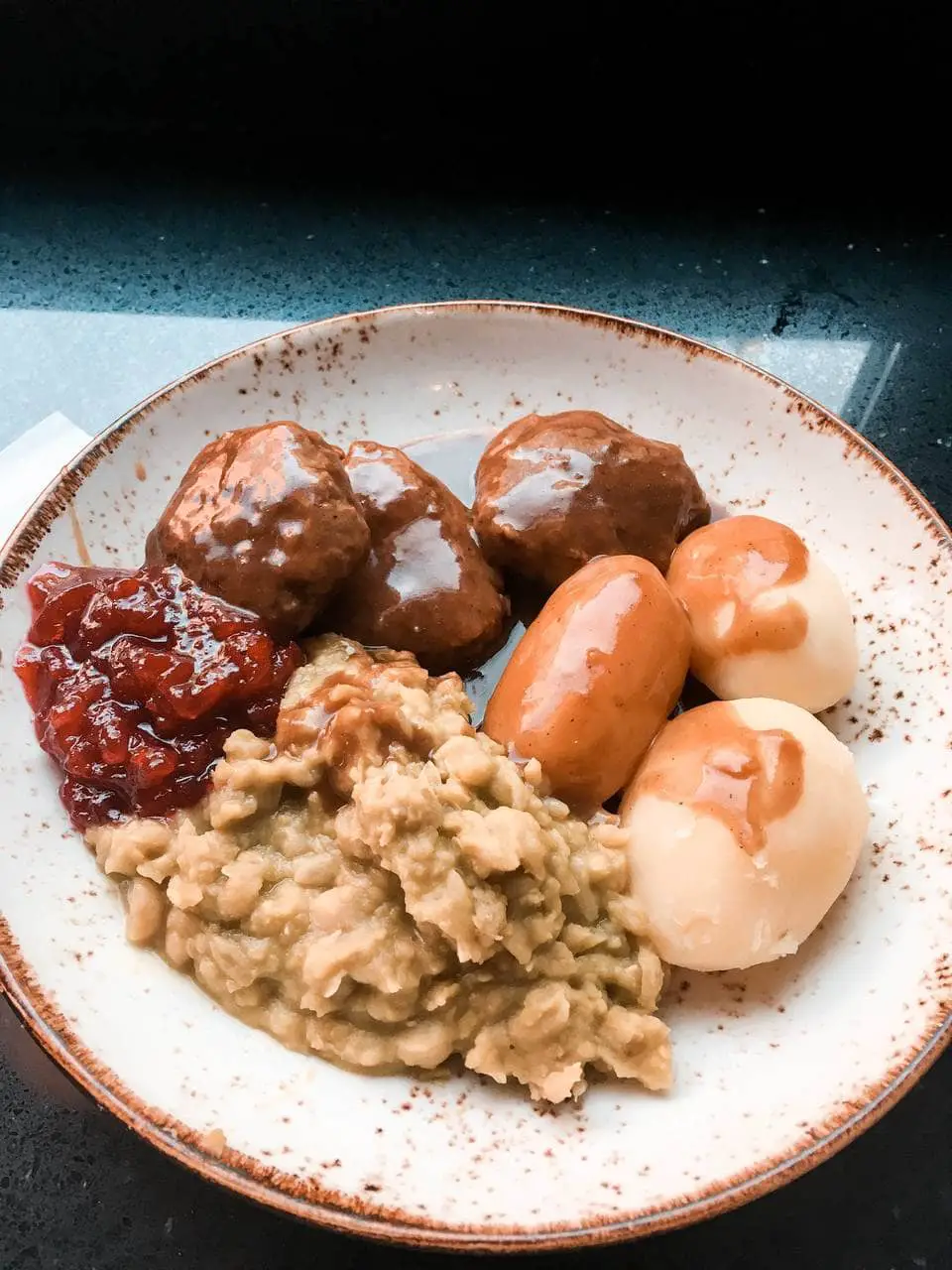 A plate of Norwegian Meatballs served with mashed potatoes, mushy peas and lingonberry jam at Kaffistova in Oslo, Norway. This is the best meal to try during your 2 days in Oslo.