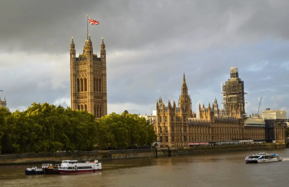 Houses of Parliament and River Thames as seen from the south of the River. The Union Jack is flying from the western tower, and the Big Ben is covered in scaffolding. This is one of the palaces in London that most people don't even realise is a palace!