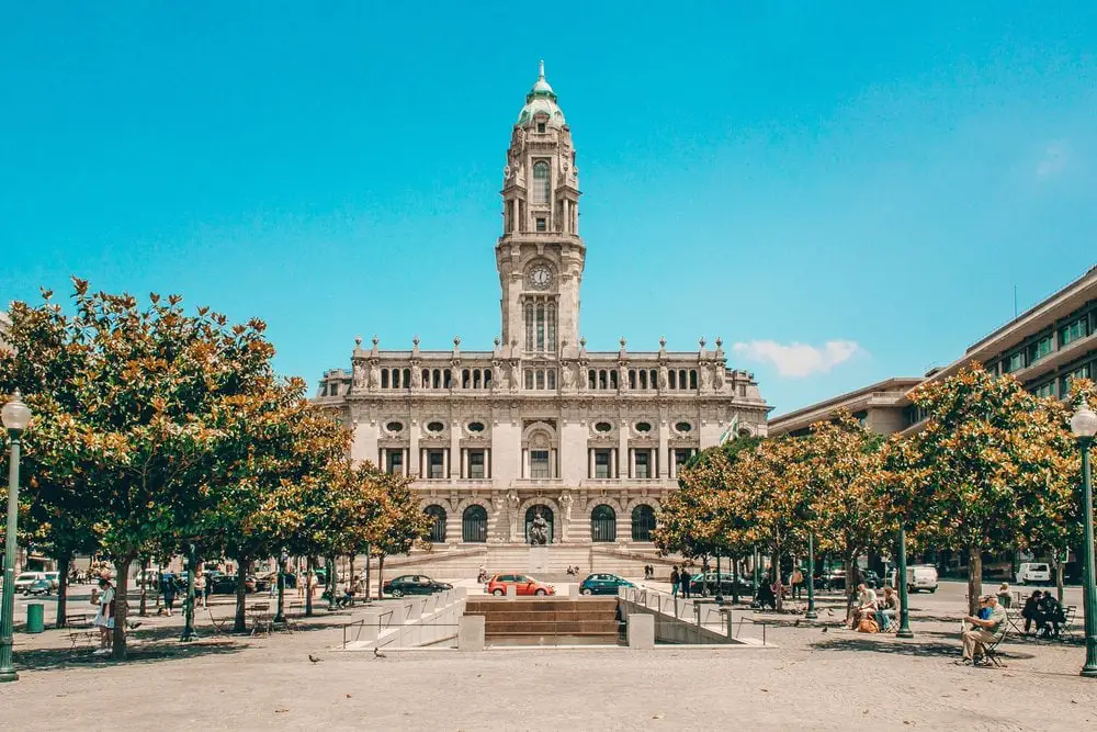 Beautiful regal-looking building in Porto surrounded by trees with yellow flowering leaves