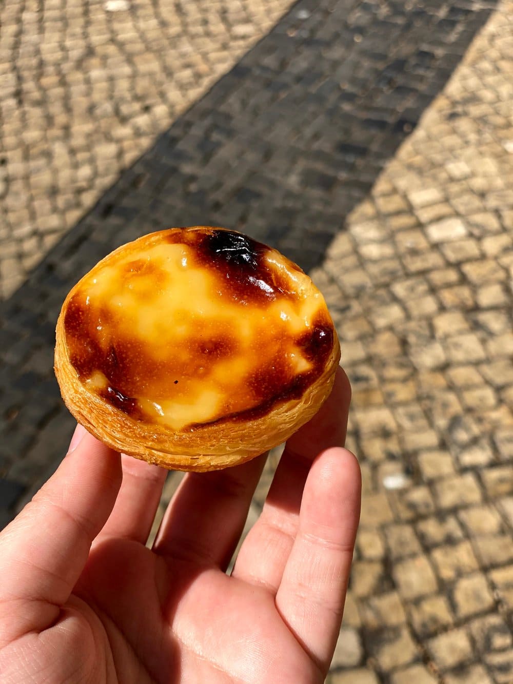 Hand holding a pastel de nata custard tart in Lisbon Portugal