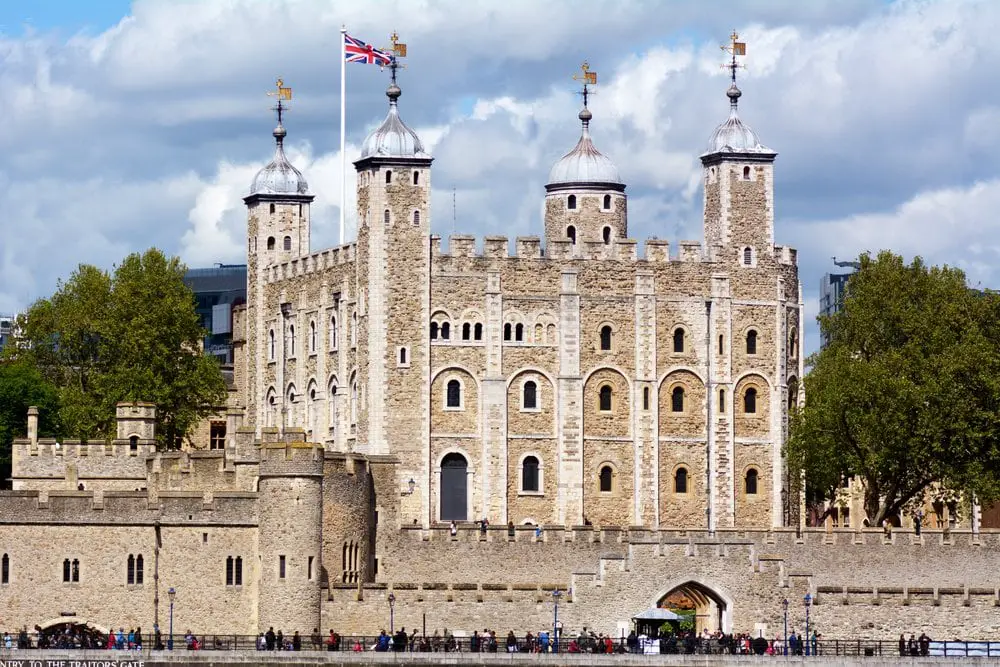 The Tower of London as viewed from the River Thames. You can see four towers above the main part of the palace, one of which has a union jack flag flying above it. This is the oldest palace in London.