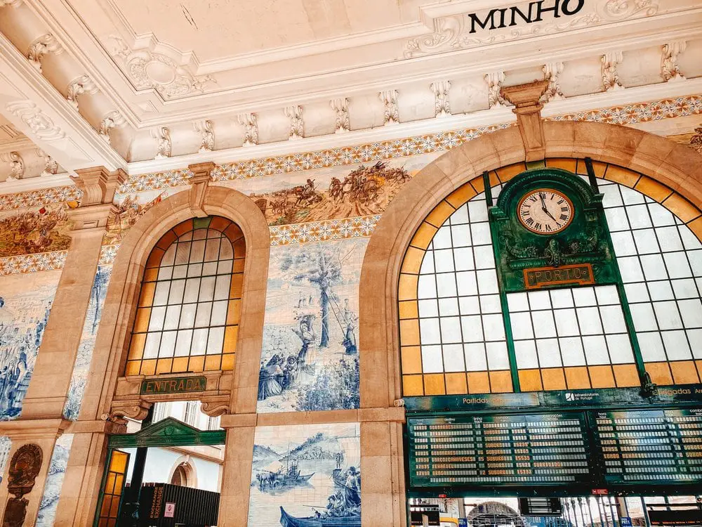 Interior of Sao Bento train station, showing the beautiful painted tiles above the departure boards.