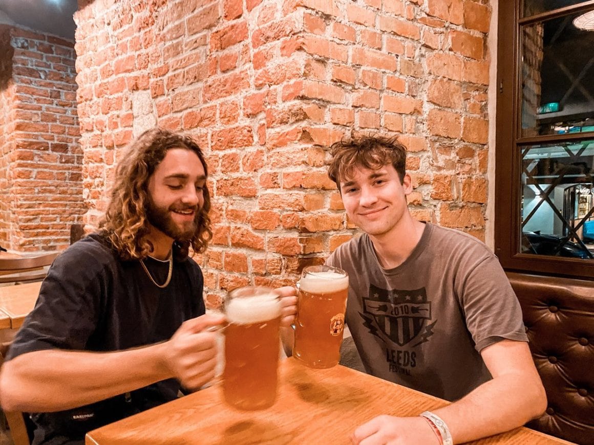 Two male friends enjoy drinking from 1 litre glasses of beer in Krakow Poland