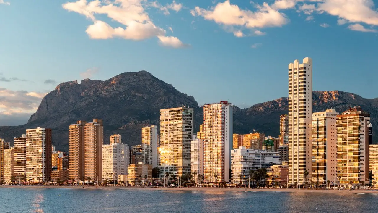 Towering buildings and skyscrapers with mountains in the background and the ocean in the foreground in Benidorm. Benidorm is one of the most popular towns on the Costa Blanca to visit.