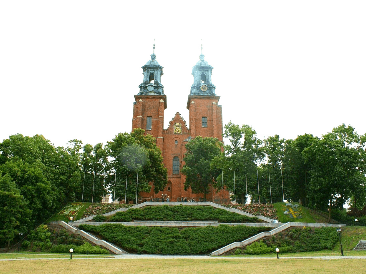 The Gothic architecture of the Gniezno Cathedral rises above a manicured lawn, one of the best places to visit from Poznan.