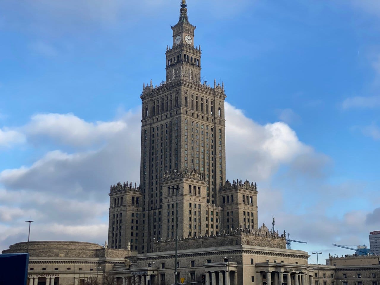 The imposing Palace of Culture and Science in Warsaw, Poland, stands tall against a backdrop of blue skies and fluffy clouds. Entry is cheap, meaning that your average daily travel budget for Poland and Warsaw can be incredibly low.