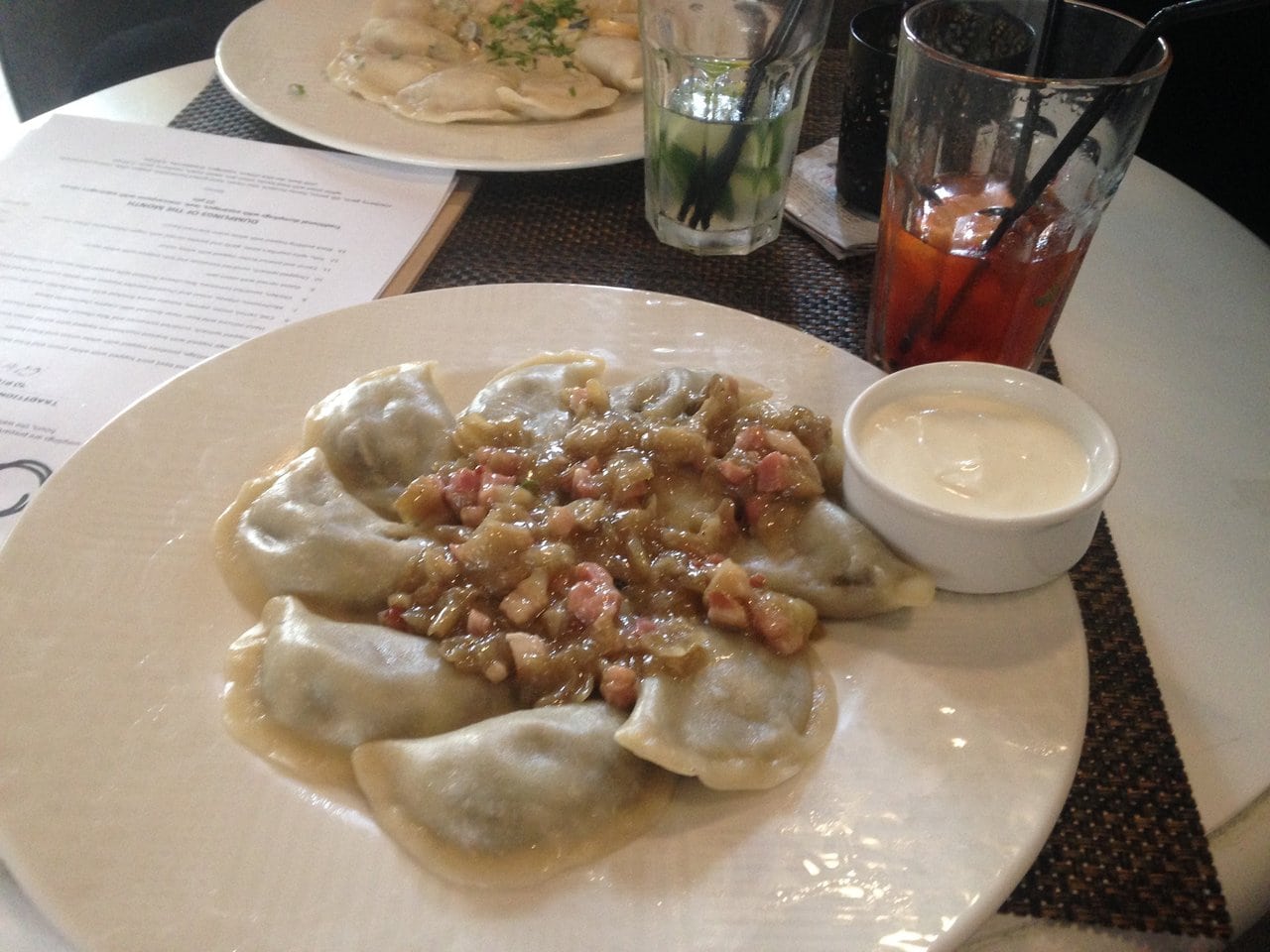 Traditional Polish pierogi on a plate with a side of sour cream. Part of the reason the cost of travel in Poland is so low is thanks to all the affordable Polish food!