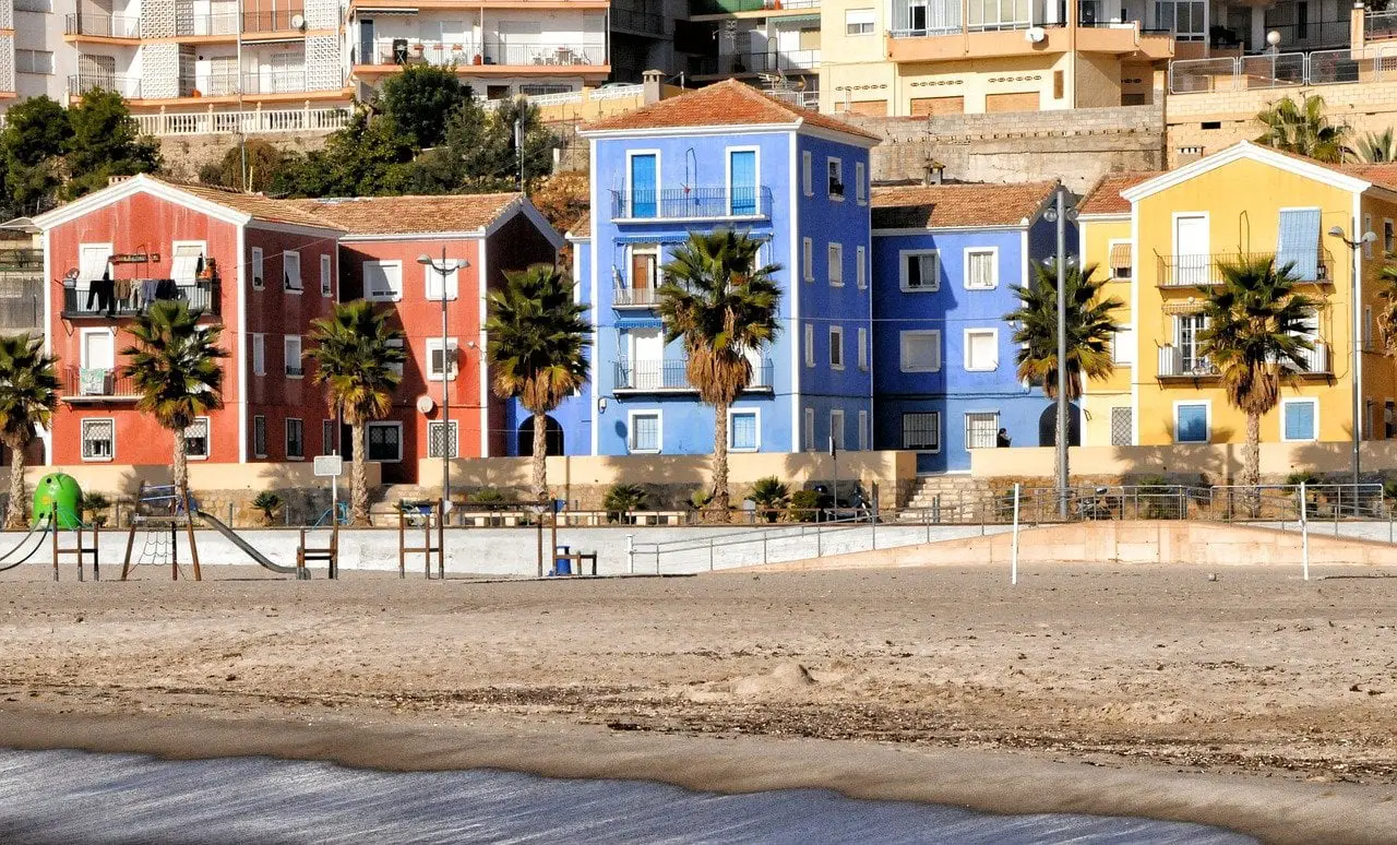 Colourful buildings painted in red, blue and yellow behind a sandy beach at Villajoyosa, one of the most colourful towns on the Costa Blanca.