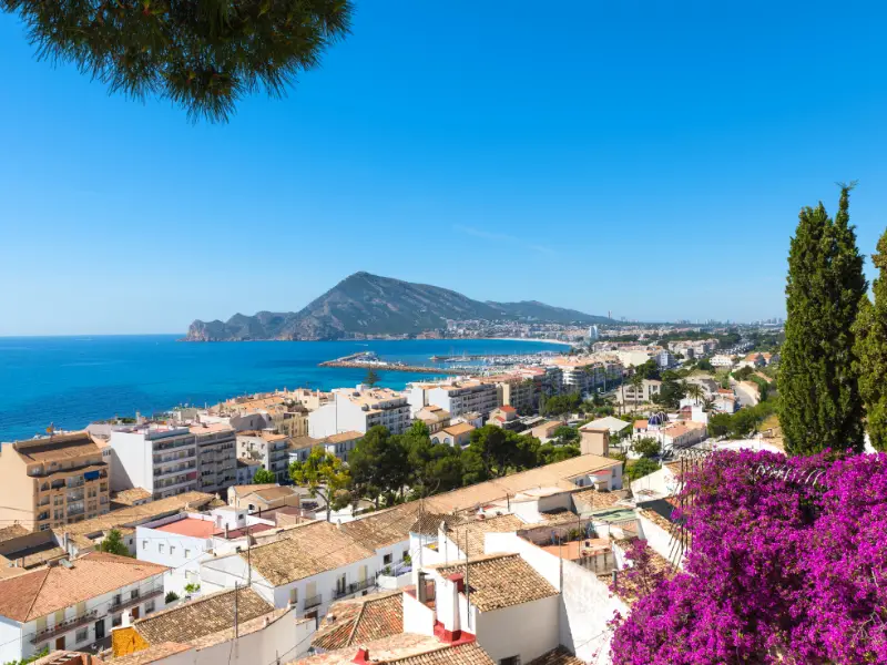 Panoramic view of the orange rooftops of Altea Spain with the blue ocean and hills in the distance.