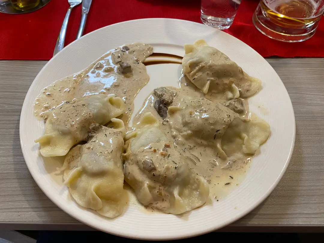 A plate of traditional Poznan-style pierogi with a creamy sauce served in a local restaurant.