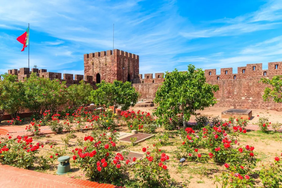 The grounds of Silves Castle in Portugal, surrounded by red flowers.