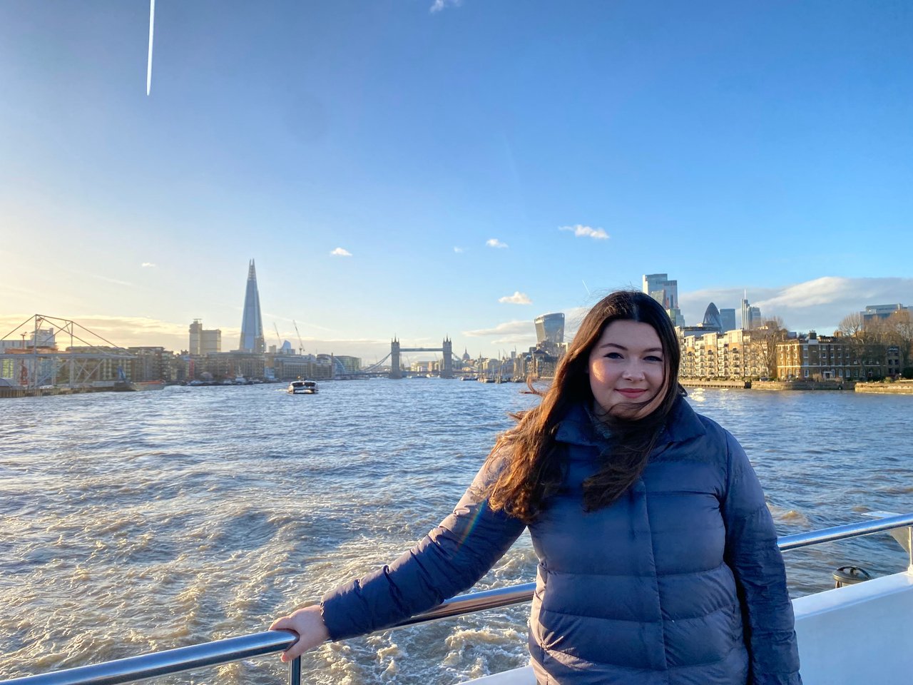 Ella standing on a River Thames boat cruise, with the London Shard in the background.