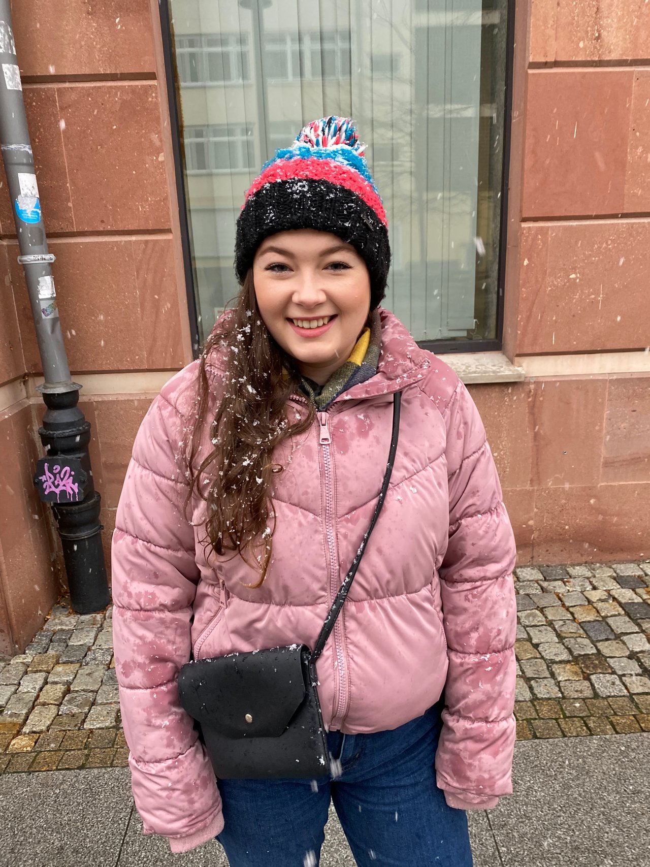 Ella wearing a pink coat and woolen hat on a winter day trip to Wroclaw Poland