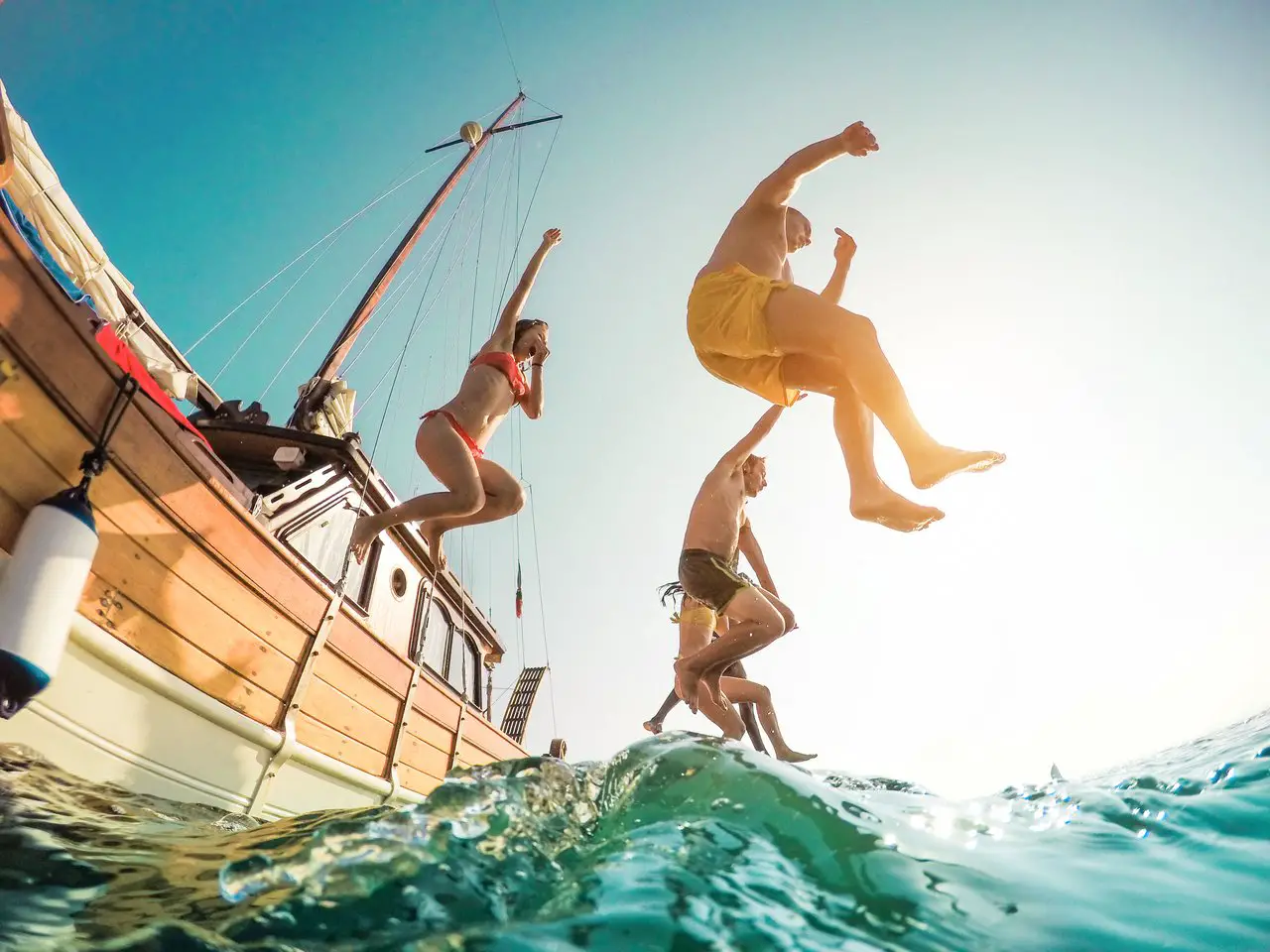 People jumping off a small boat into the ocean