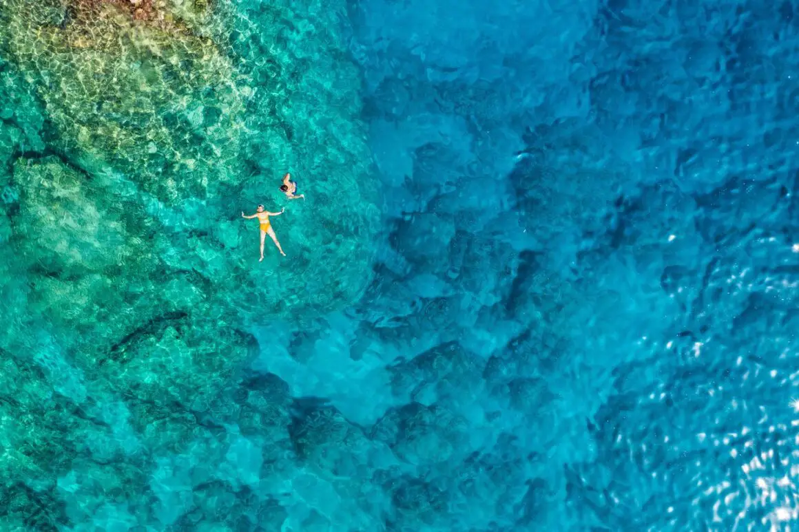 Drone photo of somebody floating on blue ocean