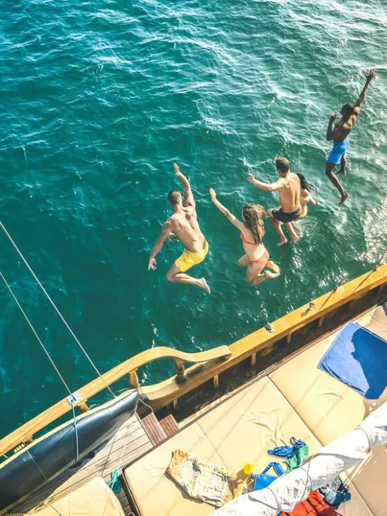 People jumping off a boat into the sea on a party boat