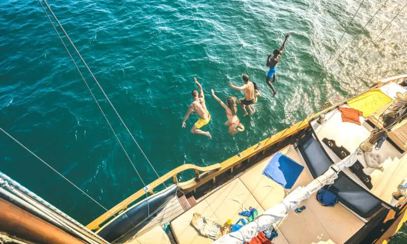 People jumping off a boat into the sea on a party boat