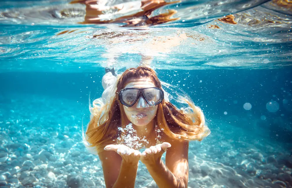 Snorkelling woman blowing a kiss underwater in the tropical sea on Paros boat tours.