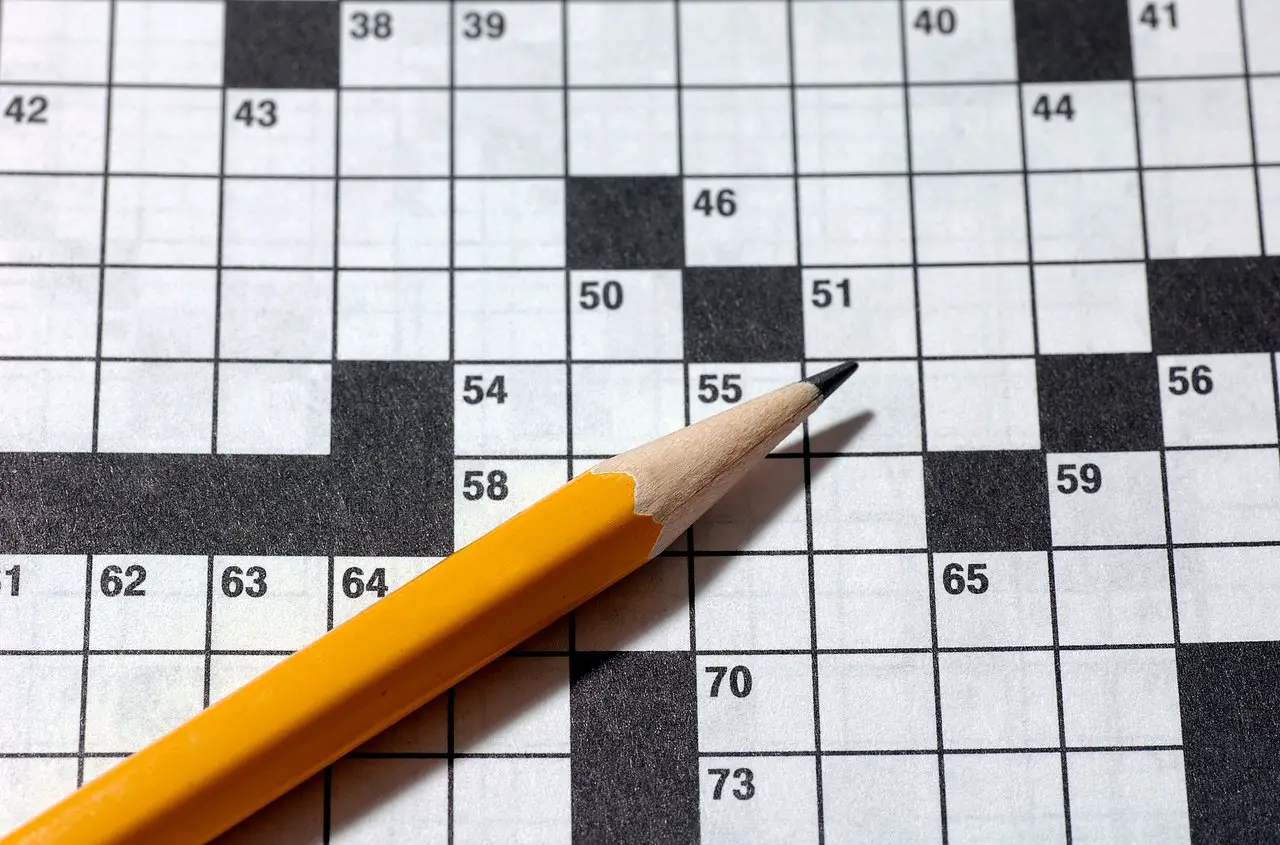 Blank Crossword puzzle with an orange pencil lying on top
