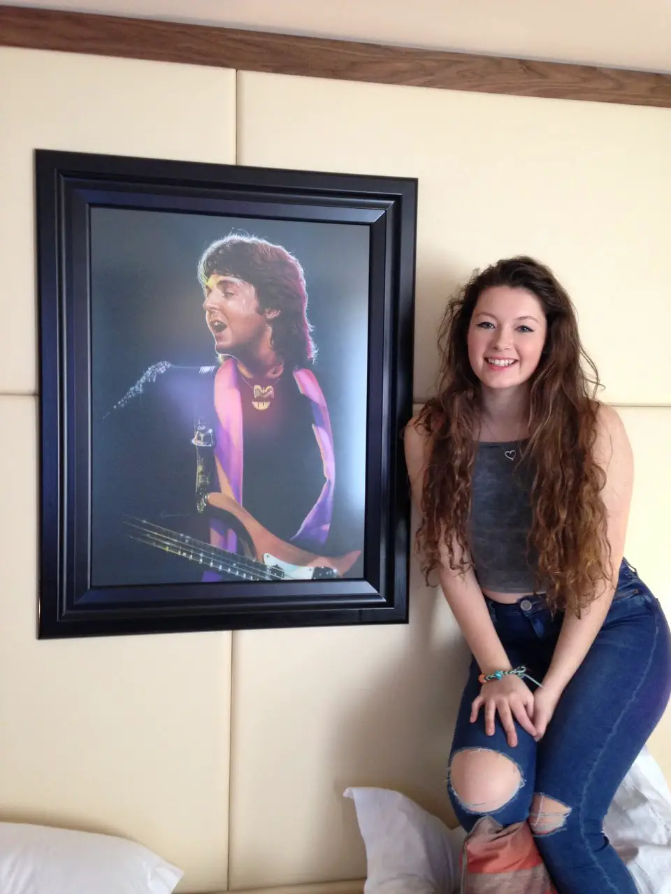 Ella standing next to a portrait of Paul McCartney in her hotel room at the Hard Days Night Hotel in Liverpool