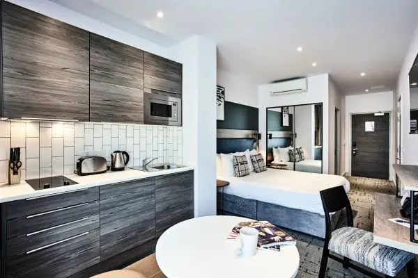 Inside the Liverpool serviced apartments called Quest Liverpool City Centre, showing a double bed, coffee table and kitchenette