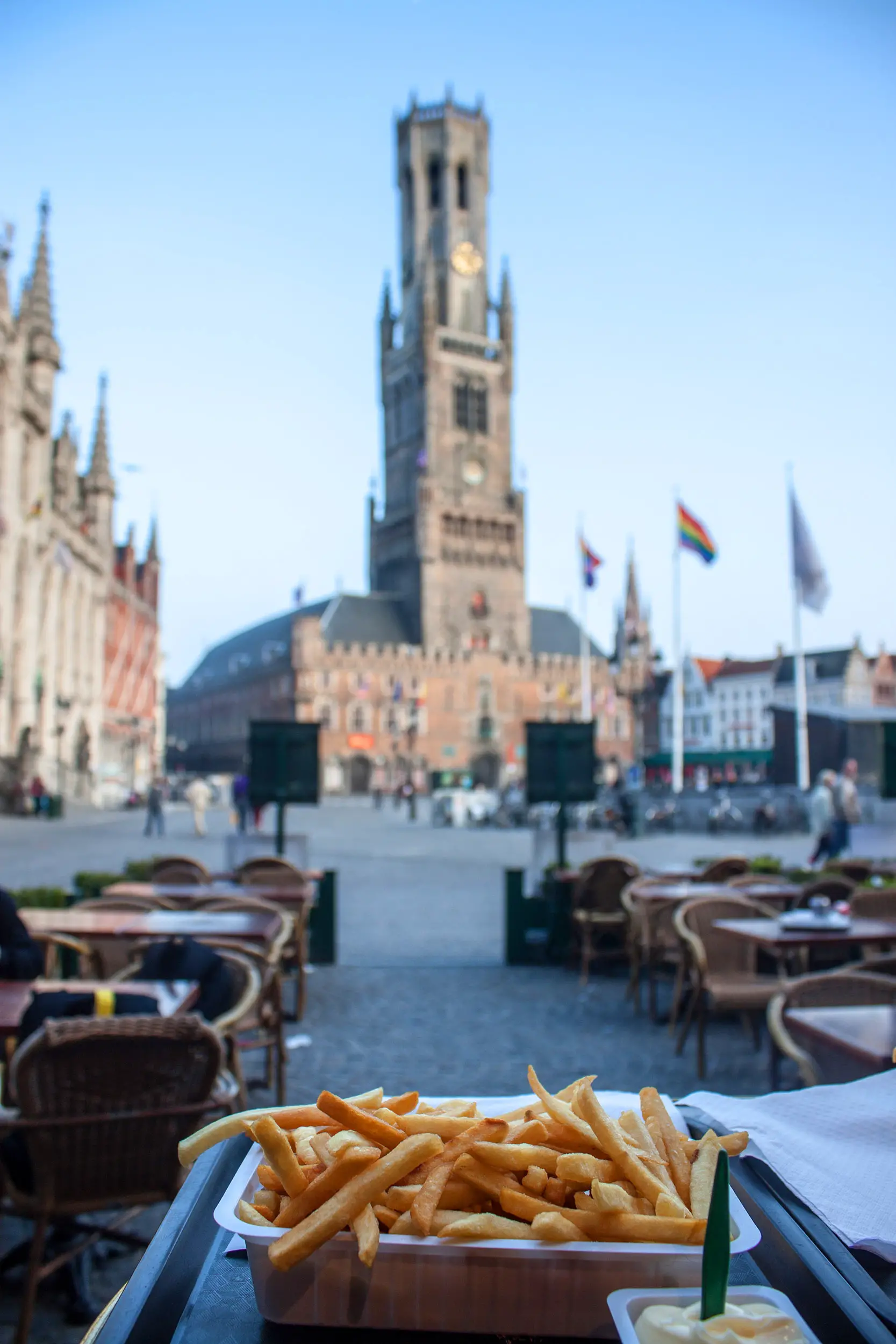 Belgian fries in front of the Brugge Belfort which can be seen on a Bruges day trip