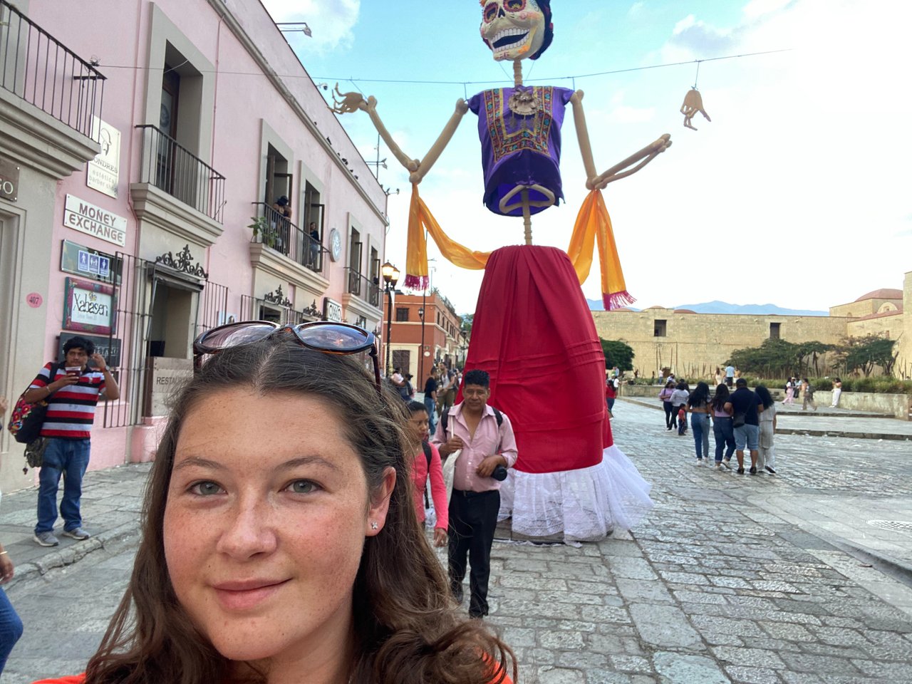 Ella standing in front of a huge clothed skeleton used as part of the Oaxaca day of the dead parade