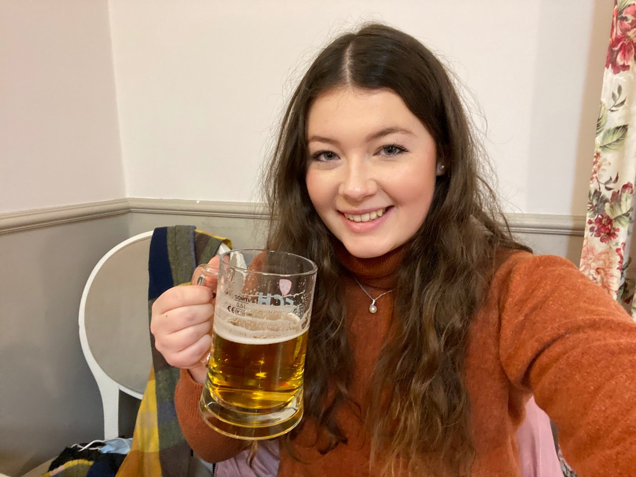 Ella smiling whilst holding a 500ml glass of Polish beer on a trip to Poland