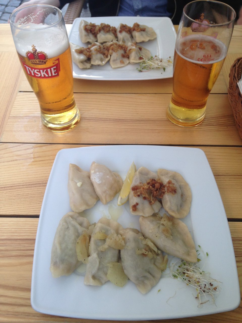 Two square plates of Polish pierogi with two Polish beers