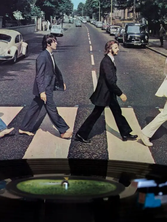 Beatles Abbey Road album cover behind a turntable playing the Abbey Road LP