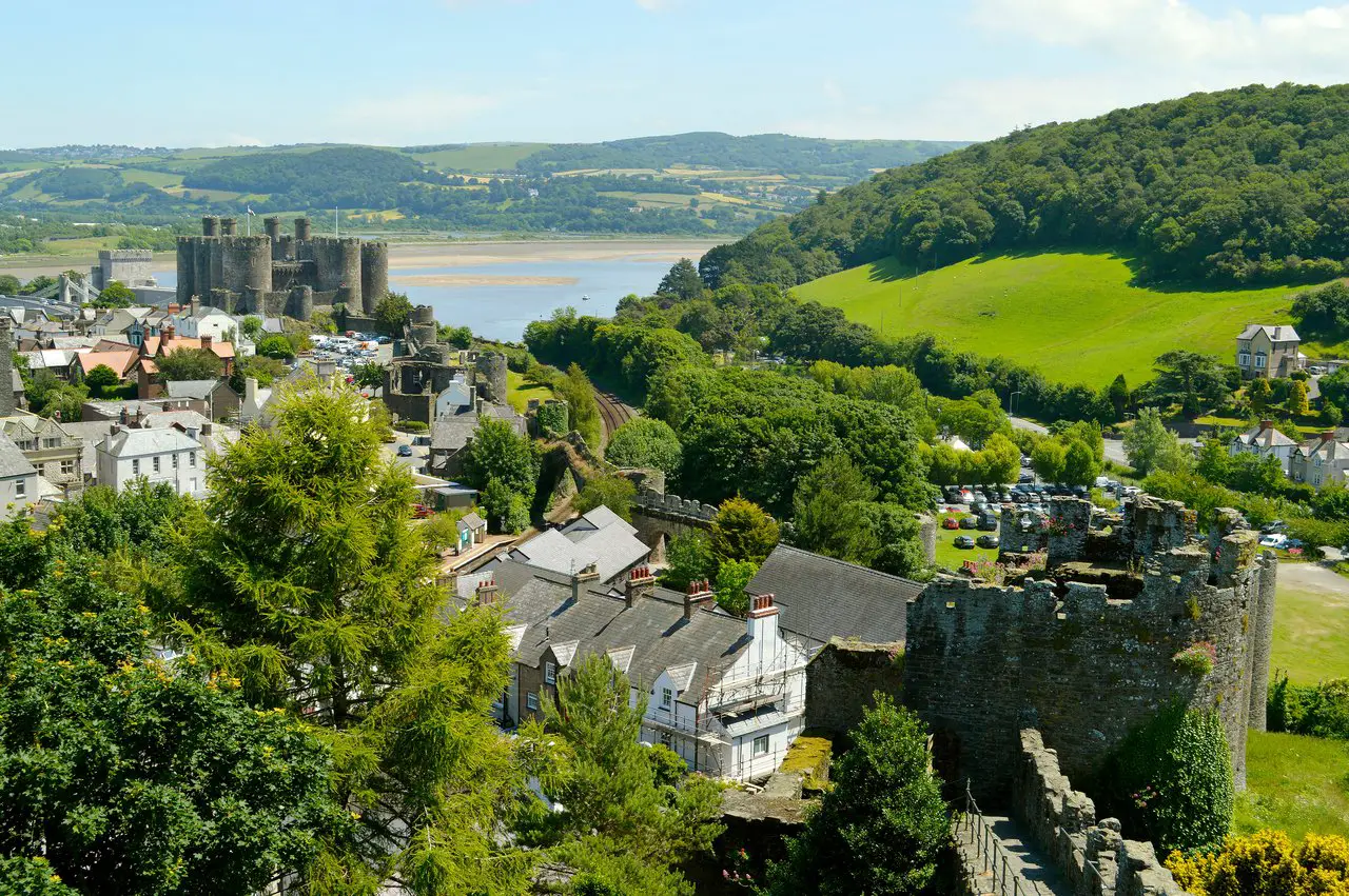 Conwy Castle in North Wales, surrounded by green fields and trees, and with a river in the background