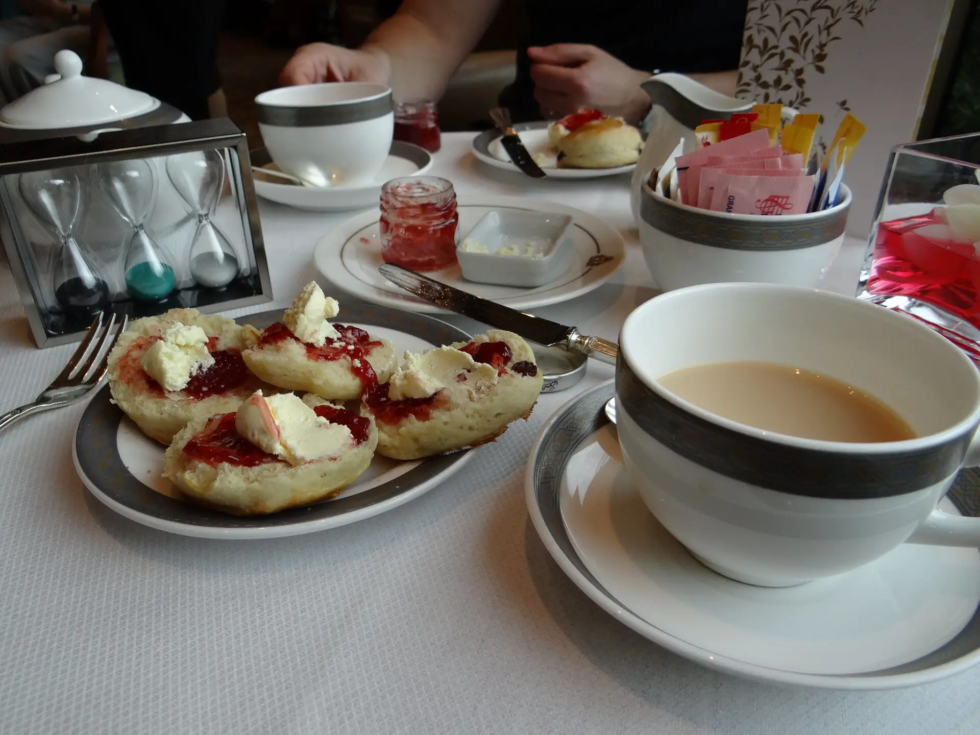 Two cups of tea and two plates of scones with jam and clotted cream