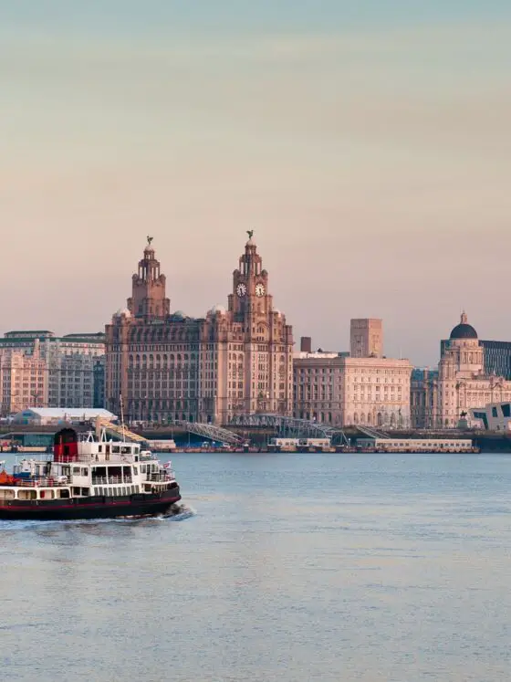 The Mersey Ferry sailing along the River Mersey with Liverpool at dusk in the background - you can see the Liver building and Museum of Liverpool in the background
