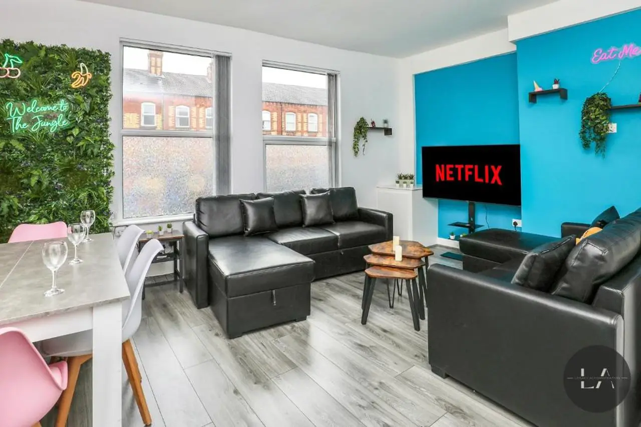 A large living room with painted blue walls and a large TV showing Netflix. This is one of the best hen apartments in Liverpool
