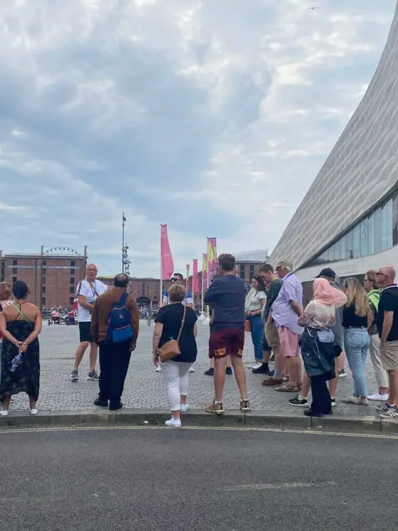 A group of people on a walking tour next to the Museum of Liverpool