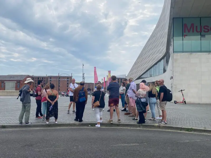 A group of people on a walking tour next to the Museum of Liverpool