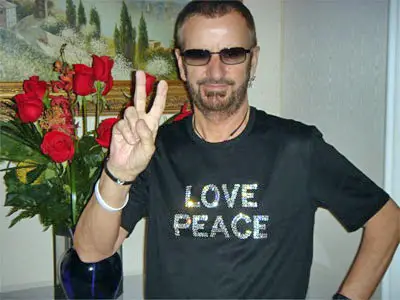 Ringo Starr in 2007, wearing sunglasses, a black t-shirt that says "love peace", holding up the peace sign.