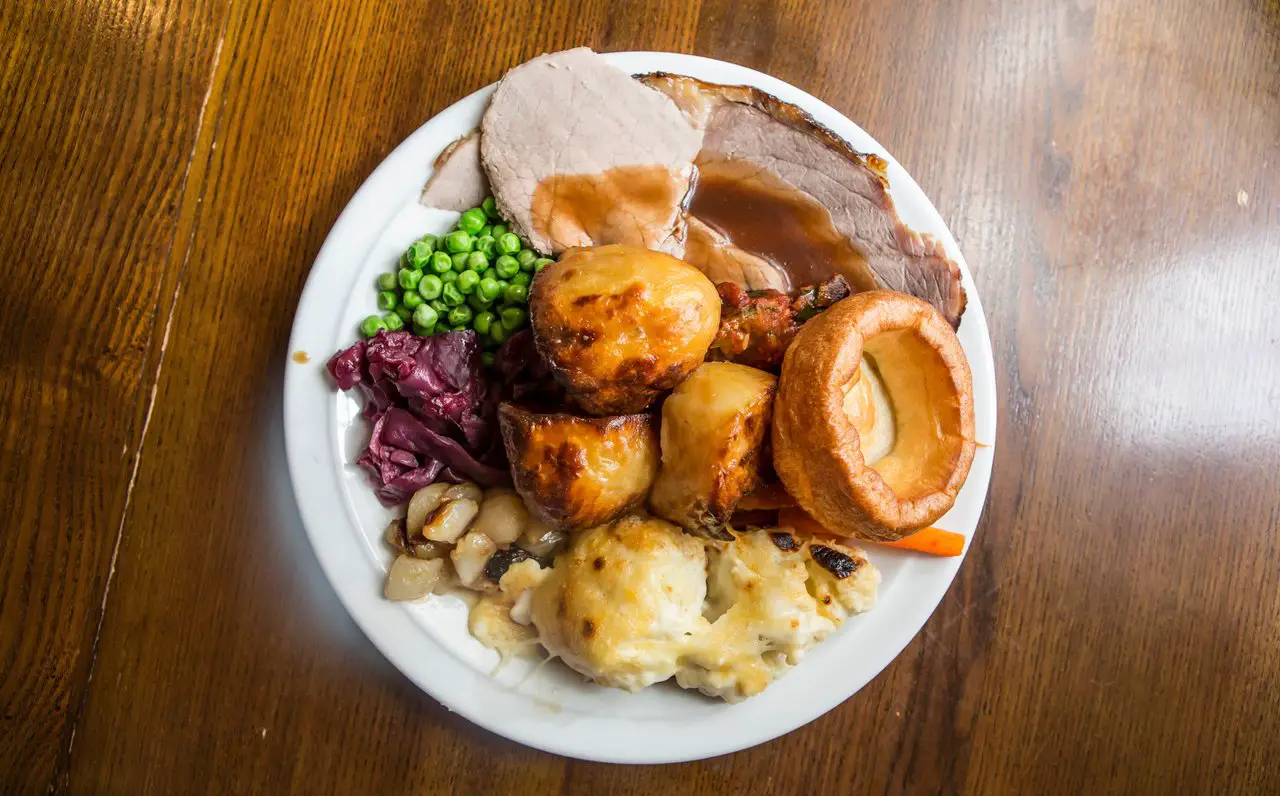 a large roast dinner on a plate on a wooden table. Liverpool is full of great Sunday lunch options like this.