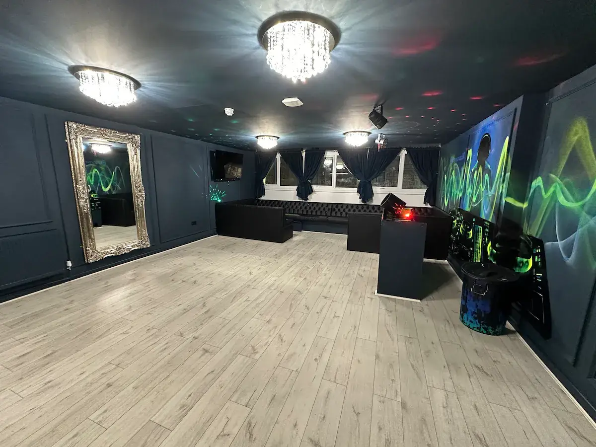 Huge living room of this party apartment, showing party lights and a DJ booth with a dancefloor. This is one of the top stag apartments in Liverpool