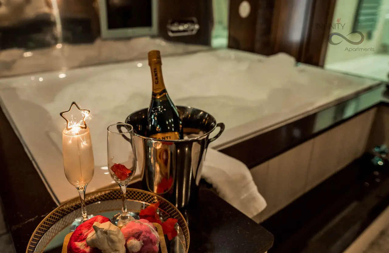 Bottle of champagne in ice with a glass of champagne next to it, in front of a bubbling hot tub. This is one of the top Liverpool party apartments for large groups like stag or hen parties.