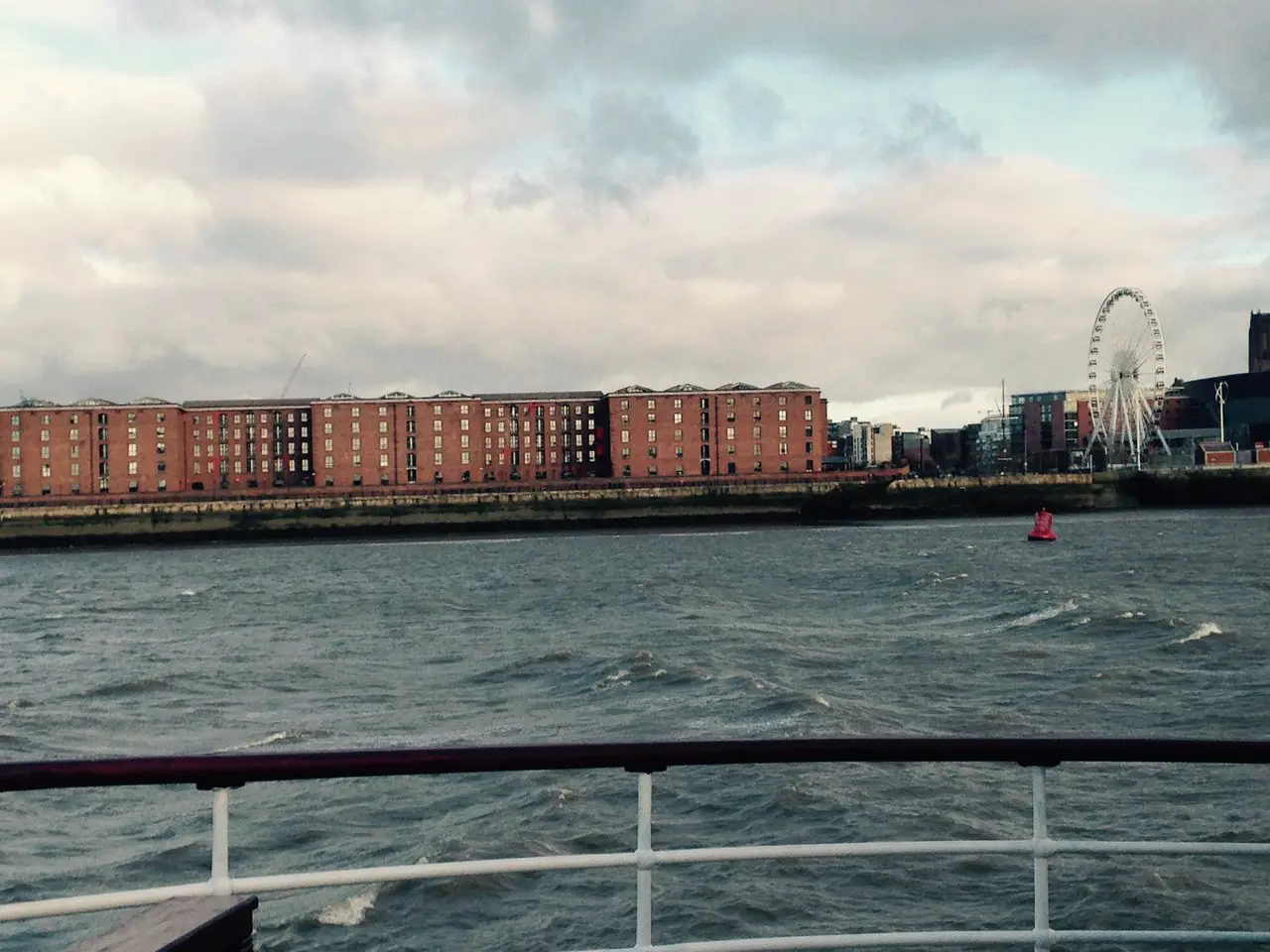 View of the Albert Dock from a boat tour on the River Mersey. It's a dark and stormy day in winter.