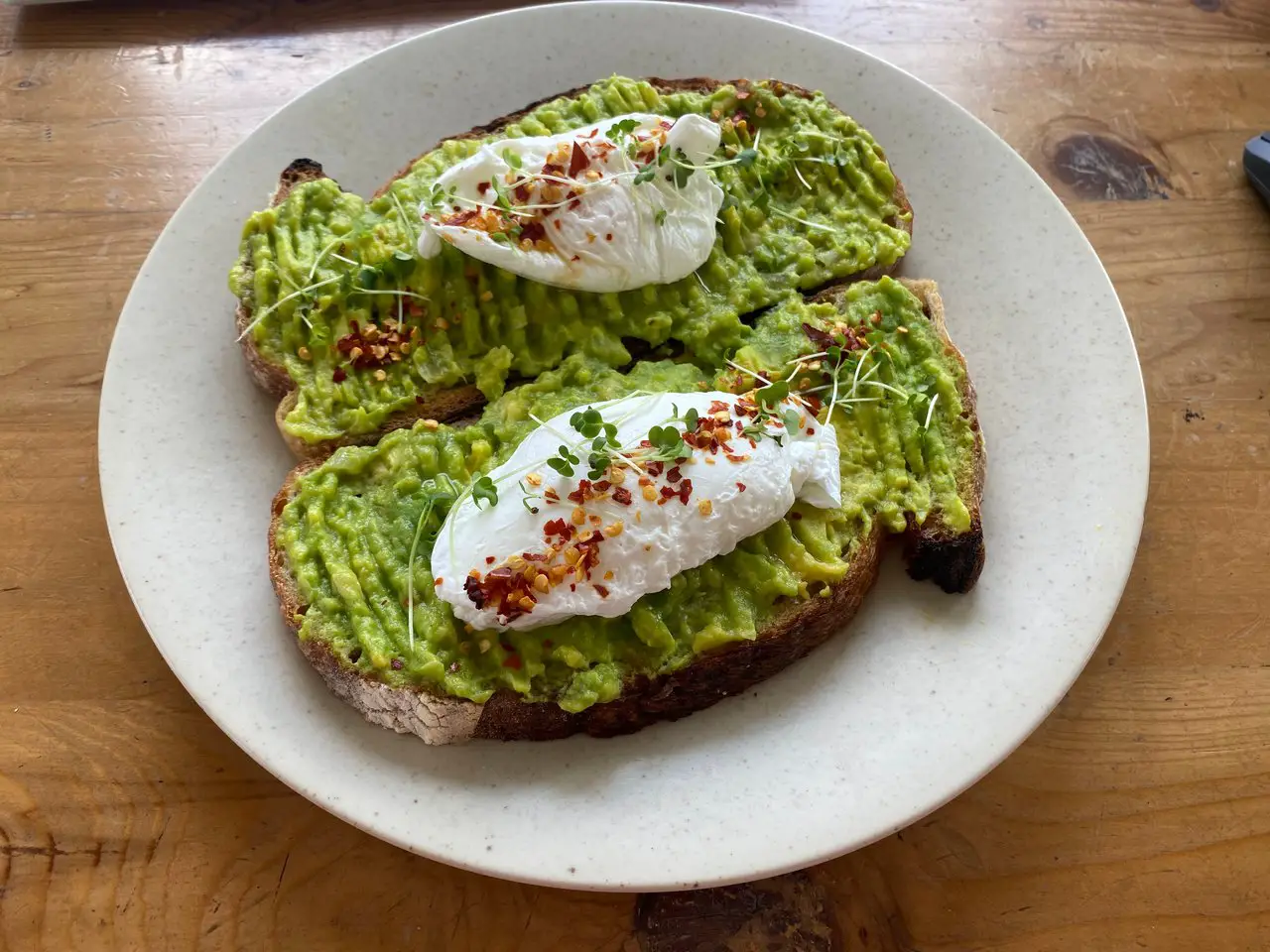 Two slices of avocado toast with poached eggs, one of the most popular dishes for breakfast in Liverpool