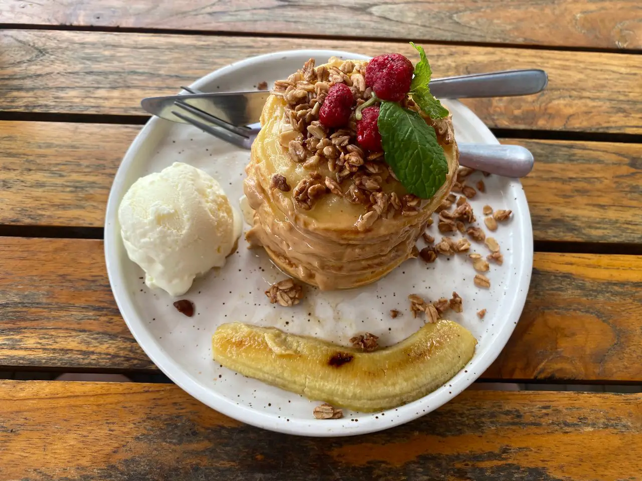 A stack of banoffee pancakes on a plate, with a scoop of ice cream and a banana. These are some of the best pancakes in Liverpool