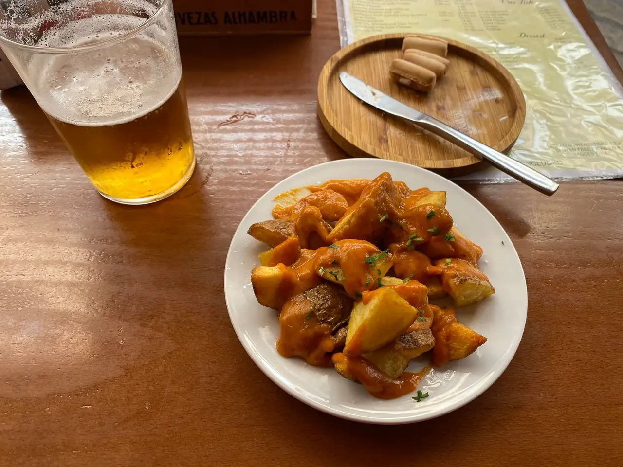 A plate of patatas bravas with a pint of Spanish beer.