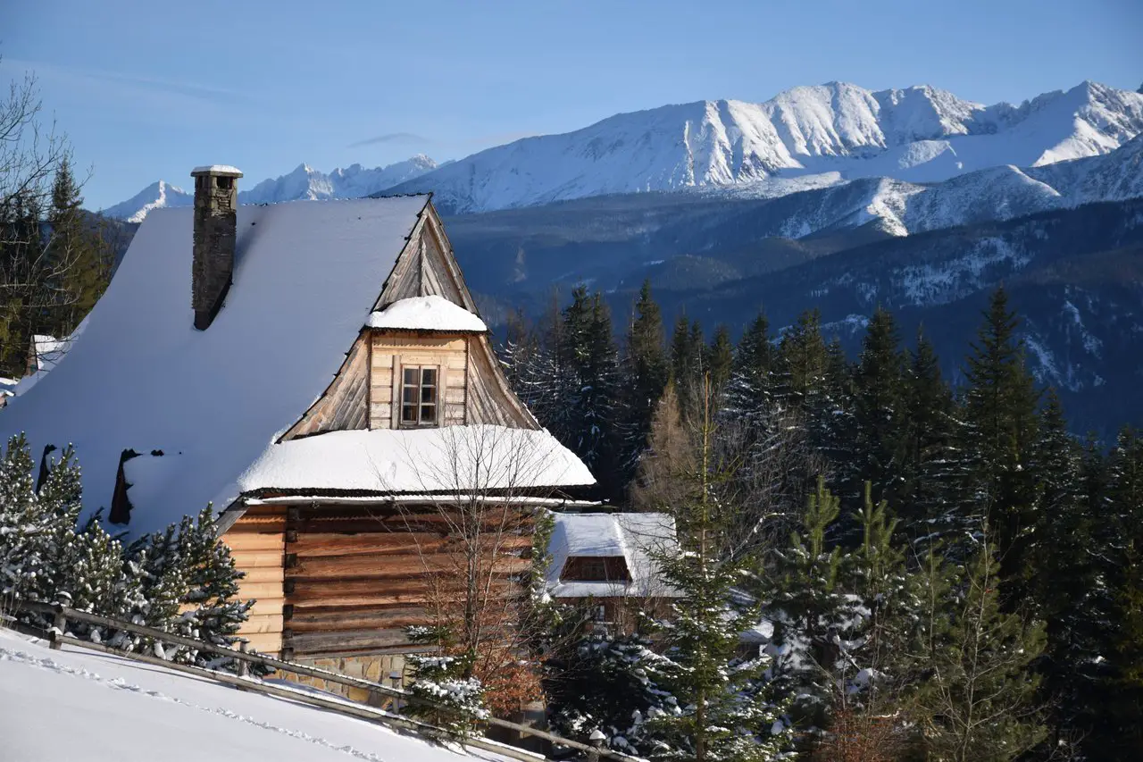 Wooden hut covered in snow surrounded by mountains in Zakopane Poland